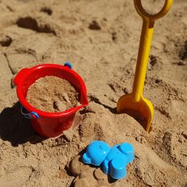 Bild von einem Sandkasten mit Schaufel und Eimerchen